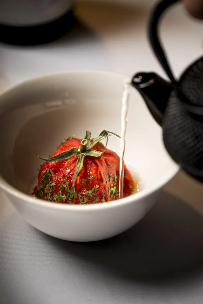 Plato con tomate y caldo servido en una cena Corpinnat