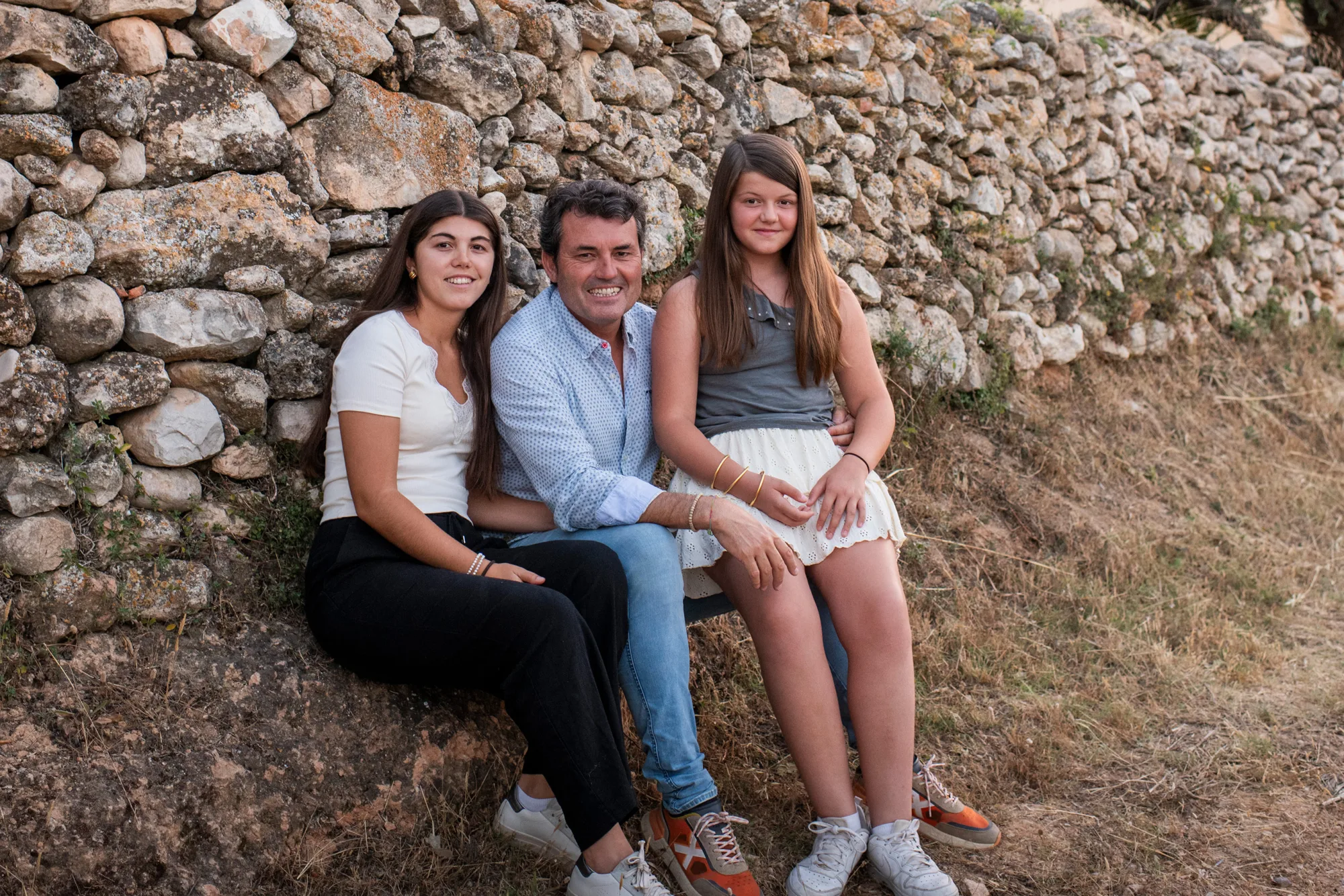 The Mas Vilella family sitting on a stone wall