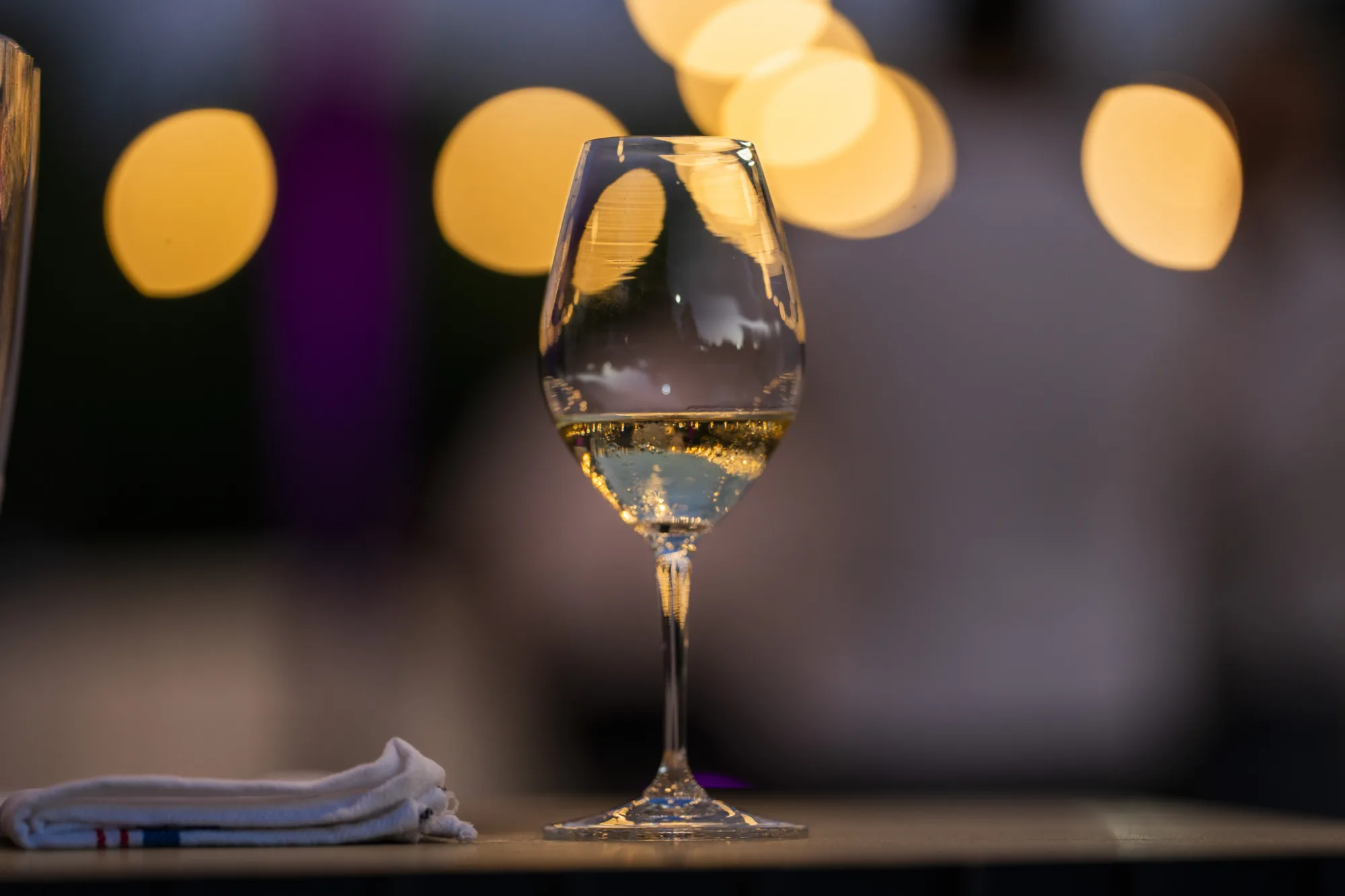 Glass of sparkling wine with lights behind
