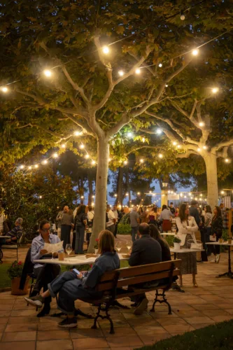Comensales bajo guirnaldas de luces en una velada Corpinnat